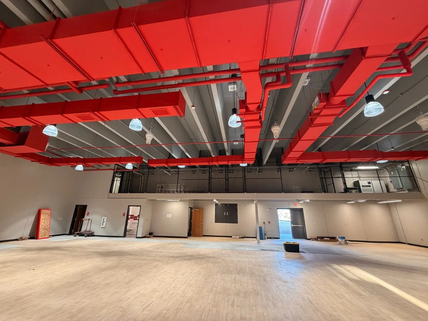 A structural ceiling and ductwork sprayed in red by DGR Painting Contractors